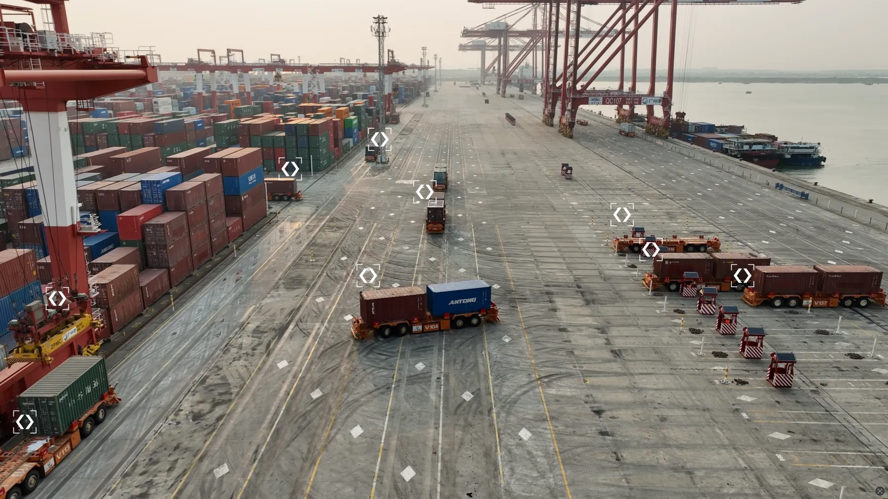Autonomous container vehicles moving cargo across a port terminal, each tracked by a targeting marker